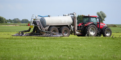 A tractor driving through a field fertilizing the crops