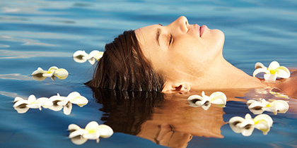 Woman lying in a lake surrounded by flowers